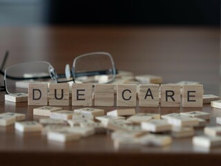 due care word or concept represented by wooden letter tiles on a wooden table with glasses and a book