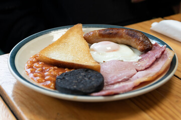 Full English breakfast - also known as a 'fry-up' - consisting of eggs, sausage, back bacon, beans, toast, and black pudding.