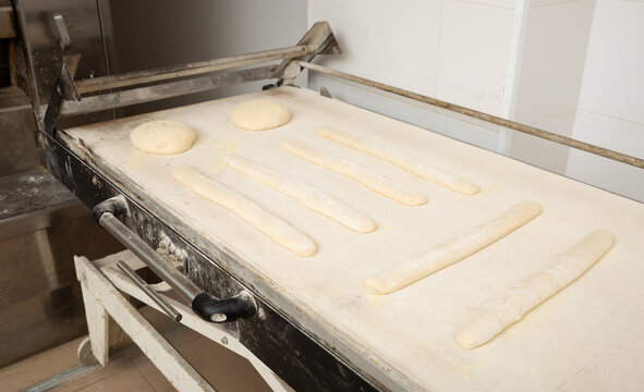 Proofing Loaves Of Bread And Baguettes On Working Surface In Baker Workshop. Traditional Baking Technique