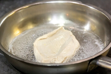 raw fresh chicken breast seasoned with oil and herbs on an old cast-iron frying pans on wooden rustic background close up top view