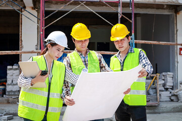 Architects and Engineers and Builders Holding a blueprint discussing building construction plans at the outdoor site. Real estate project concepts, building construction cooperation.