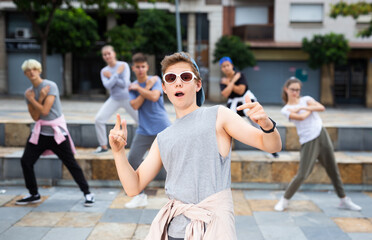 Obraz premium Confident teenager street dancer posing during performance with group in summer city .