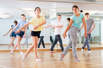 Fototapeta na wymiar Positive teenage dancers doing dance workout during group class
