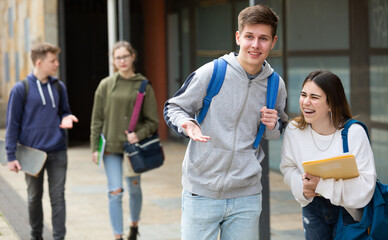 Two students discuss past lessons at a college on the street