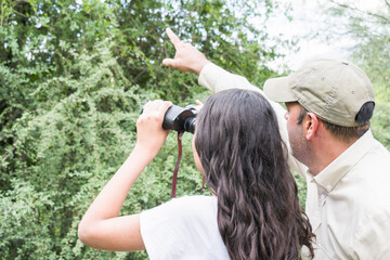 Mature Park Ranger indicates to a young student with binoculars the location of a protected species...
