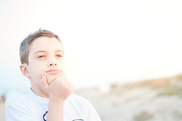 Cute preteen kid thinking and planing portrait outdoors. Ten years old kid gesturing with his face. Children emotions concept.