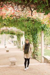 A beautiful Caucasian woman walks alone through a vine arch park and garden Square Marcel Bleustein Blanchet in Paris, France