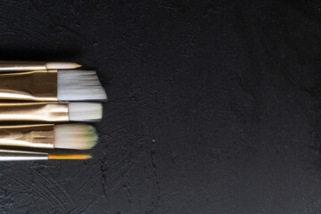 vista cenital de diferentes pinceles de cerda suave sobre fondo de madera negra 