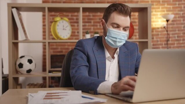 A young man in the office is typing something on a laptop, then someone drops his hand to him to say hello, but the young man in response gives him a fist. Slow motion 4k footage