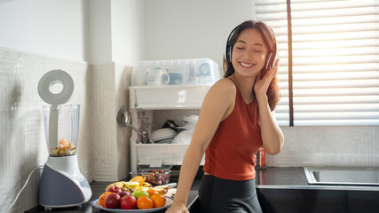 woman listening to music through headphones in the kitchen at home - lifestyles concepts