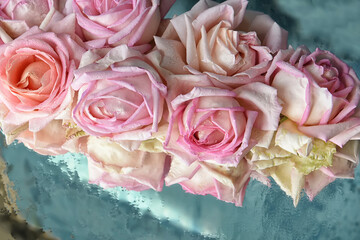 Delicate pink roses on a wet surface.