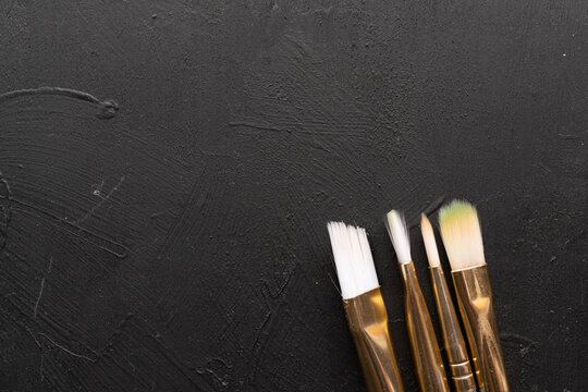 vista cenital de diferentes pinceles de cerda suave sobre fondo de madera negra 