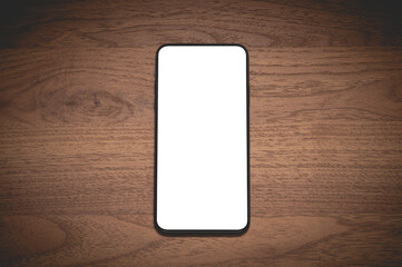 Close up smartphone with an empty white screen on the wooden table at the cafe.