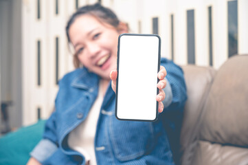Close up relax women showing a smartphone with an empty white screen lazy on the sofa at home.