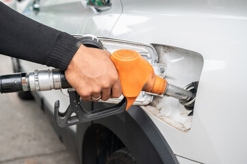 Someone hand holding nozzle for refueling car from gas station or petrol station.