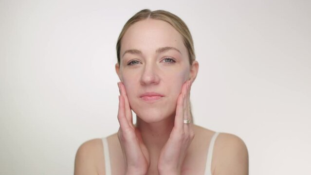 Makeup Tutorial: Blonde model applies face primer with fingers, circular motion