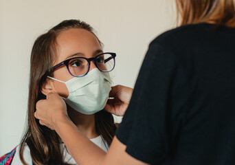 Mother adjusting the mask to her kid before she goes to school