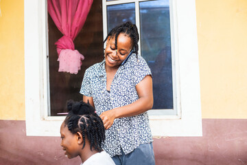 young exciting African female hair dresser making and receiving phone call