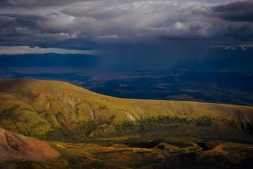 Downpour in the mountains. Heavy thunderclouds over picturesque hills and valleys. Beautiful natural background.