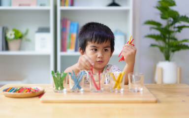 Cute asian 3 years old boy is learning to sorting the color rod to the glass, concept of homeschool, montessori, freedom, education, activity for child development and sensory activity for kid.