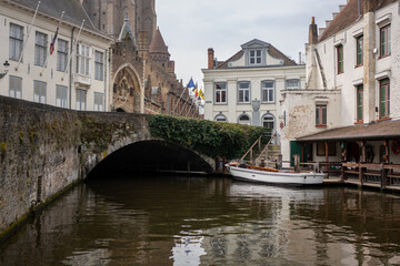 Obraz premium Moored tour boat next to a vine covered bridge in the heart of Brugge Belgium