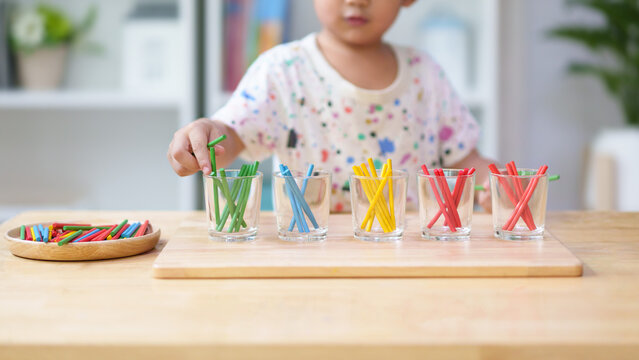 Unidentified hands of little boy learning to sorting the color rod to the glass, concept of homeschool, montessori, freedom, education, activity for child development and sensory activity for kid.
