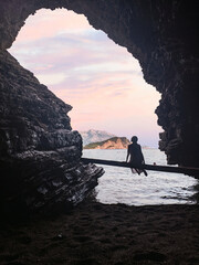 Silhouette of woman in a cave in front of a beautiful seascape on Mogren beach