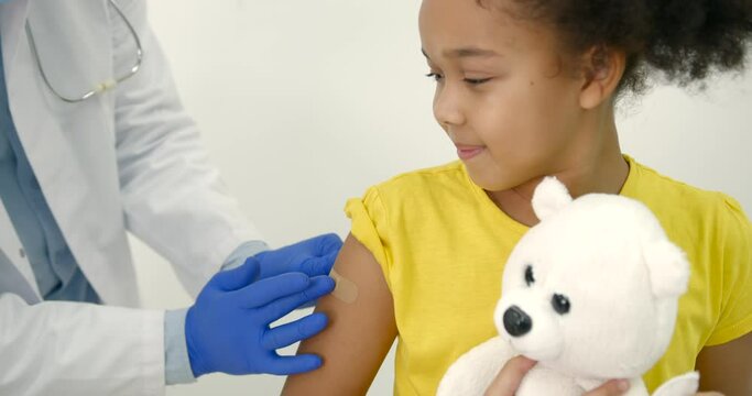 Male pediatrician giving a vaccine shot to a black kid