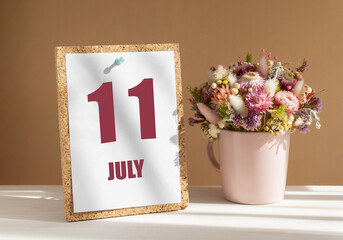 july 11. 11th day of month, calendar date.Bouquet of dead wood in pink mug on desktop.Cork board with calendar sheet on white-beige background. Concept of day of year, time planner, summer month