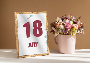 july 18. 18th day of month, calendar date.Bouquet of dead wood in pink mug on desktop.Cork board with calendar sheet on white-beige background. Concept of day of year, time planner, summer month