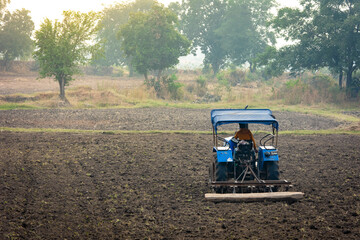 Indian farmer working with tractor in agriculture field