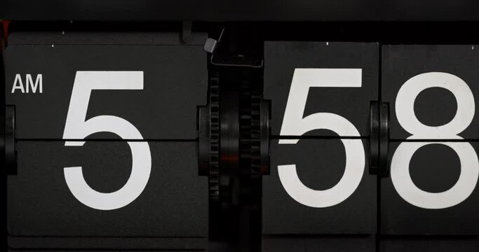 Display black digital clock turns one minute to 5.59 am.