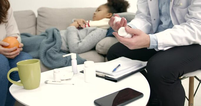 Pediatrician and mother near little black girl at home