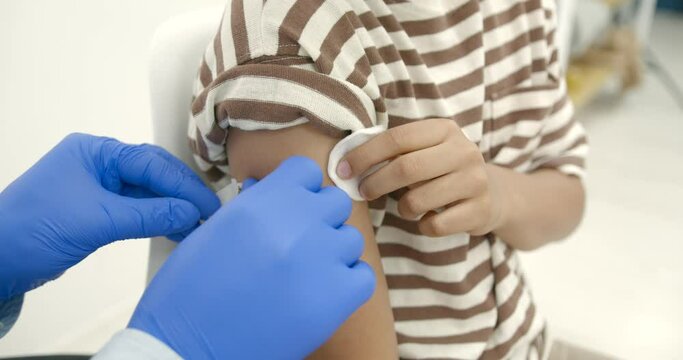 Male pediatrician giving a vaccine shot to a black kid