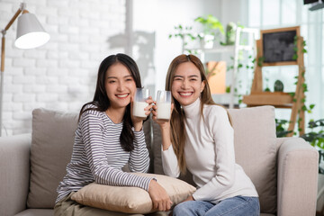 Young Asian women couple is drinking organic fresh milk together.LGBTQ couple lesbian holding milk...