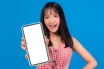 Obraz premium Beautiful Asian woman cute girl in red dress with bangs hair style smiling good mood showing big smart phone with blank screen , white screen isolated blue background , Mock up Image