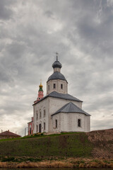 A small old Christian temple on a hill against a gloomy sky. Religion and faith. Vertical.