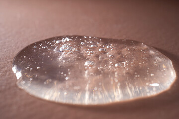 A drop of serum with bubbles on a beige background.