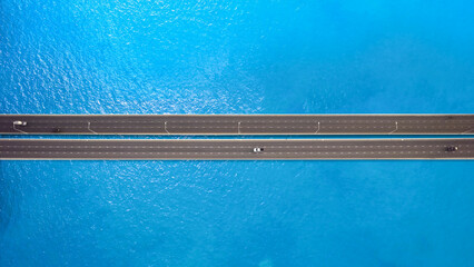 aerial view of The traffic on the bridge is fluent in traffic, contrasting with the blue water surface.