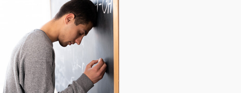 Upset arabic student near chalkboard in classroom, problems with studying in college, guy taking exam math thinking answer, education concept