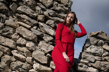 Young girl in the red dress stands among the ancient ruins.