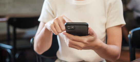 Casual Businesswoman holding and using smartphone for sms messages, young woman typing touchscreen mobile phone in cafe or modern office. lifestyle, technology, Social media and network concept