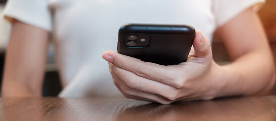 Casual Businesswoman holding and using smartphone for sms messages, young woman typing touchscreen mobile phone in cafe or modern office. lifestyle, technology, Social media and network concept