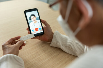 Asian senior elderly man video call with doctor in living room at home