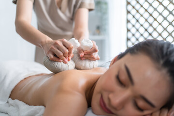 Obraz na płótnie Canvas Asian beautiful woman enjoy thai hot compress massage with herbal bag. 