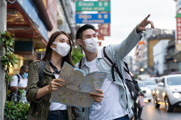 Asian romantic couple wear mask, travel in the city for honeymoon trip