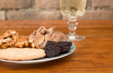 Dried fruits lie on a plate on a wooden table. A glass of wine on the table.Close-up. Selective focus.