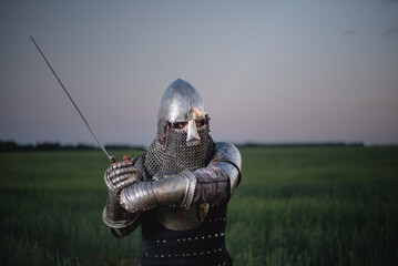 A knight in the armor and helmet with the sword battles on the battlefield concept.