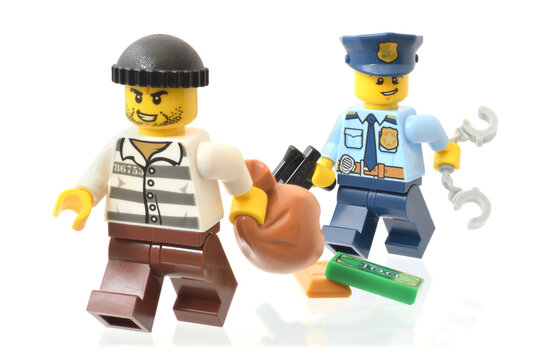 Lego minifigures of flighting criminal and following police officer. Editorial illustrative image of law and punishing. Studio shot.