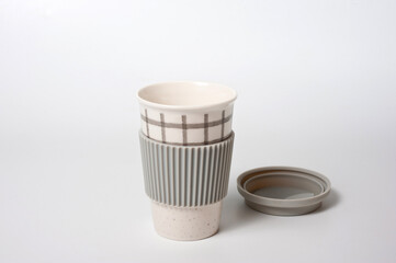Checkered ceramic cup with rubber lid, shot against a white background.